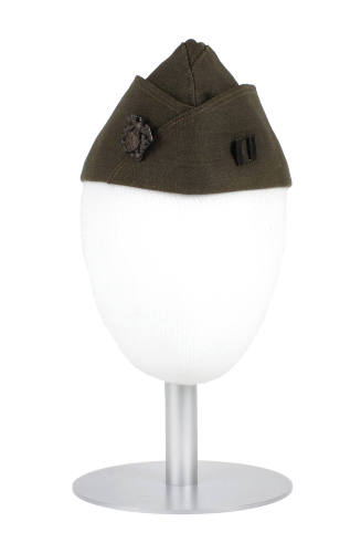 Drab green garrison cap displayed on a mannequin head form with officer insignia pins