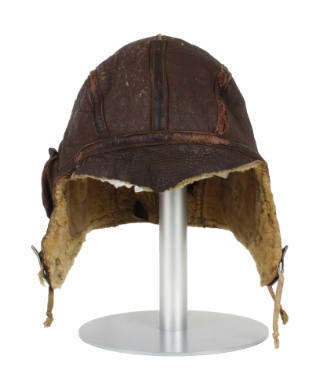 Brown leather flight helmet with visor and ear flaps on mannequin head form