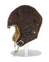 Side view of brown leather flight helmet with visor and ear flaps on mannequin head form