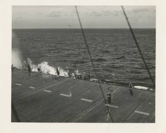 Printed black and white photograph of USS Intrepid's flight deck with smoke and flames visible …