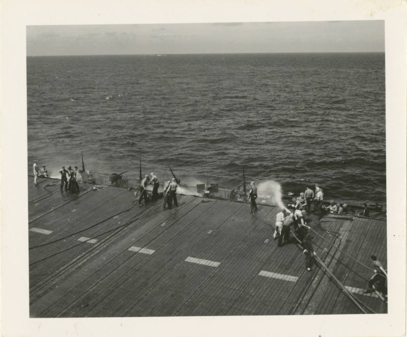 Printed black and white photograph of USS Intrepid crew members putting out the flames in Gun T…