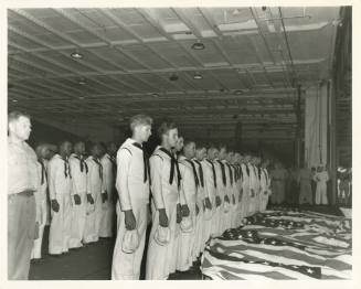 Printed black and white photograph of sailors in dress white uniforms standing at attention ove…