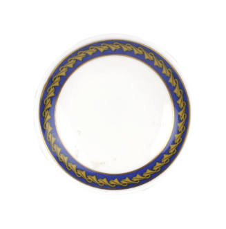 Small circular dish with repeating image of Concorde in gold on a blue background around the ri…