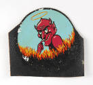Partially cut out insignia patch depicting red devil with mischievous face on blue background a…