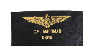 Black nametag with gold naval aviator wings image and "C.P. Amerman USNR" text