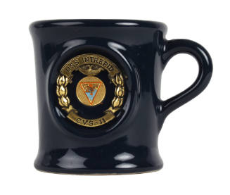Blue ceramic mug with gold insignia design in the center