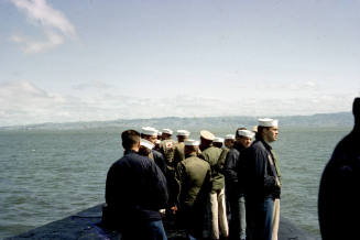 Color photograph of crew members standing topside on the submarine USS Growler