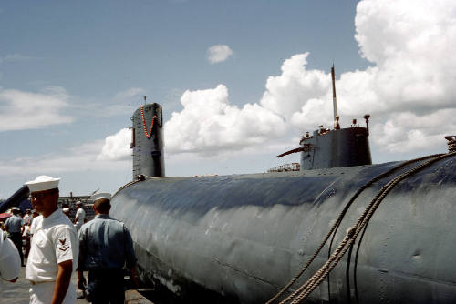 Color photograph of the submarines USS Growler and USS Grayback in port with sailors around the…