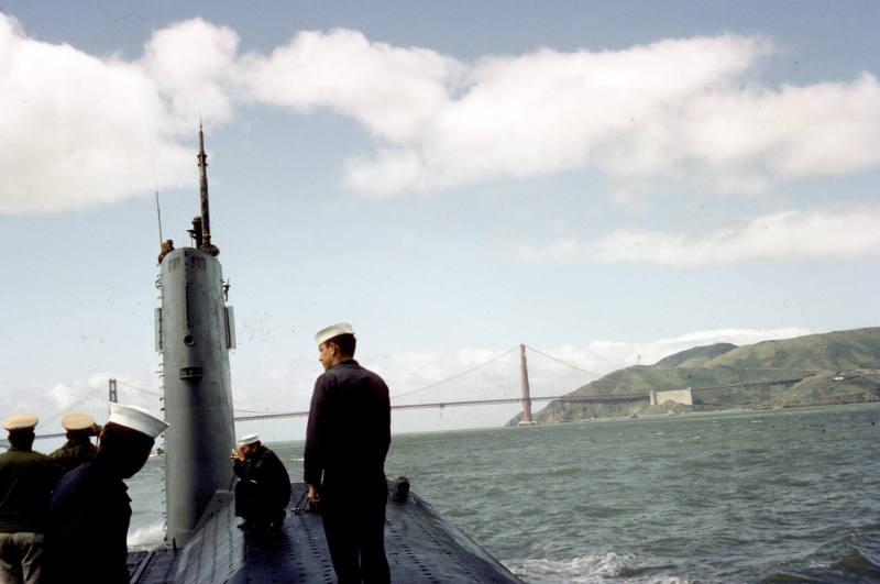 Color photograph of sailors topside on USS Growler with the Golden Gate Bridge in the backgroun…