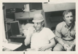 Printed black and white photograph of two men sitting in a stateroom