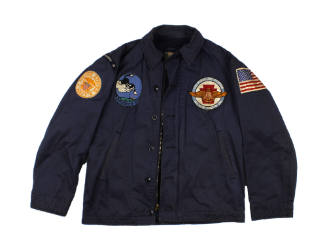 Front of dark blue USS Intrepid cruise jacket with various patches on the chest and shoulders