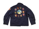 Back of dark blue USS Intrepid cruise jacket with various patches sewn to the jacket, small shi…