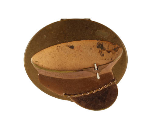 Brass oval shaped makeup compact with decorative metal piece in the shape an officer’s cap atta…