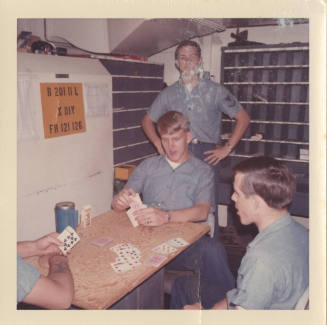 Color photograph of enlisted sailors playing cards in USS Intrepid's post office
