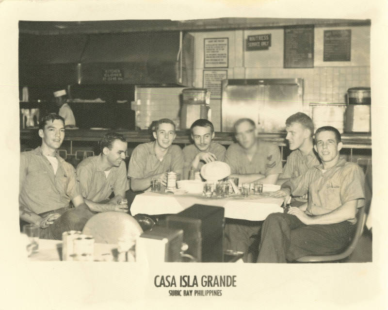 Black and white photograph of seven enlisted sailors sitting at a table at a restaurant 