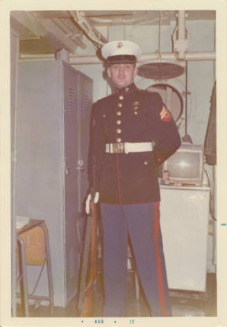 Color photograph of George Mehlig in a U.S. Marine dress uniform in a ship space on USS Intrepi…