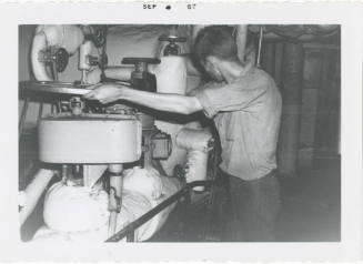 Black and white photograph of a crew member operating a boiler feed check valve