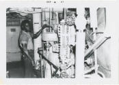 Black and white photograph of a crew member adjusting a feed check valve in a fire room