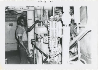 Black and white photograph of a crew member adjusting a feed check valve in a fire room