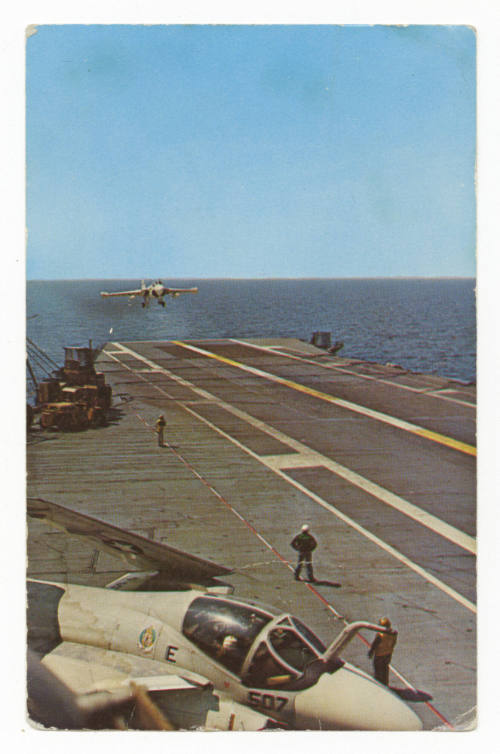 Color photograph of the flight deck on USS Yorktown with an aircraft coming in for a landing