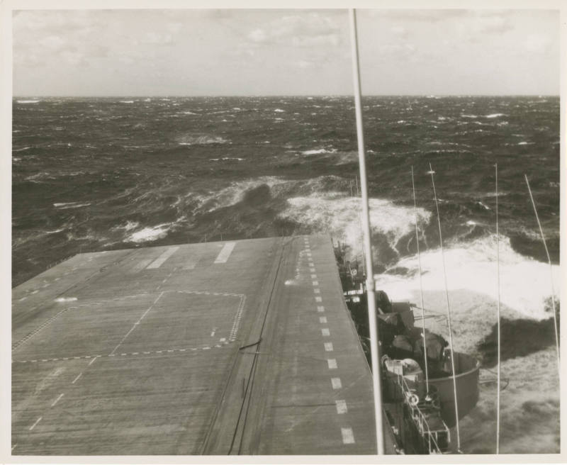 Black and white photograph of the aircraft carrier USS Intrepid's flight deck with waves surrou…