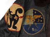 Two circular insignia patches, one with a black cat and one with gold wings and a submarine per…