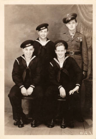 Printed black and white photograph of four men with three wearing U.S. Navy uniforms and one we…