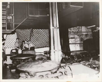 Black and white photograph of USS Intrepid's anchor chain room, with group of sailors sitting i…